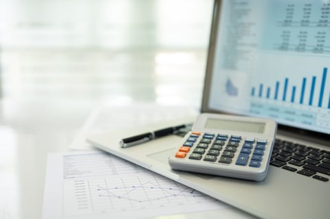 Calculator, account statement and business report on laptop computer representing accounting business concept