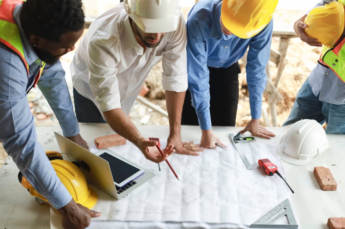 Group of engineers and staff met to discuss and work together to assess the progress of the residential construction site