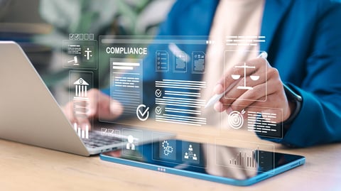 Business professional reviewing digital compliance documents on laptop and tablet representing AI regulations and tech compliance